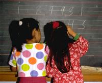 Grade 1 bilingual Hispanic girls adding a long column of 5-digit numbers 